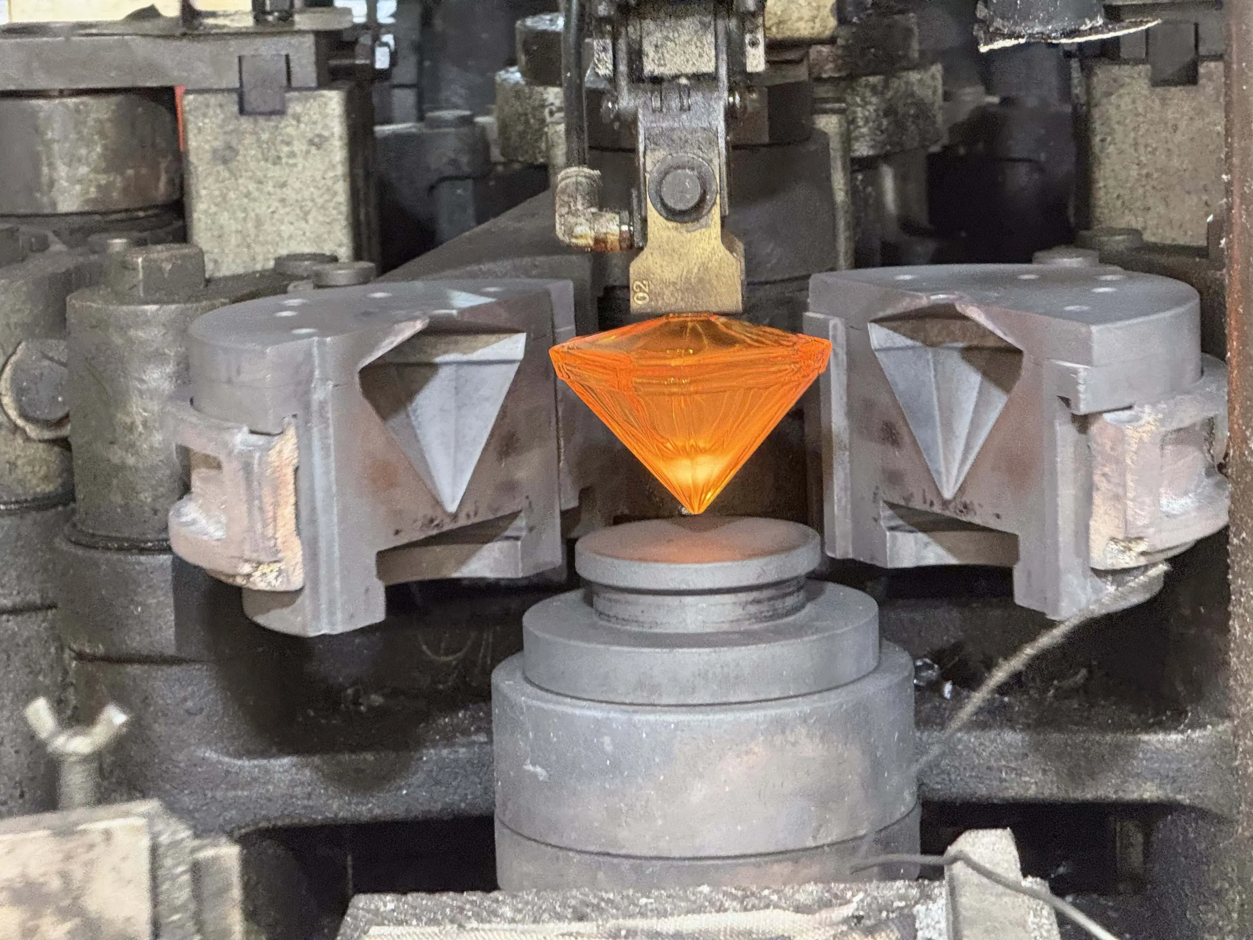 Molten glass being formed into a perfume bottle in a factory